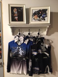 two pictures hang on the wall next to some shirts and shorts hanging from a rack