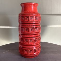 a red vase sitting on top of a table