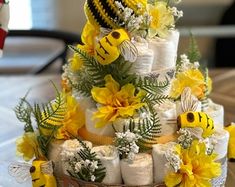 a three tiered cake decorated with yellow flowers and bees on it's sides