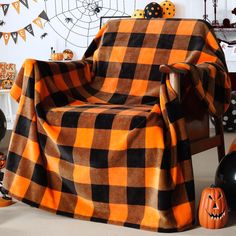 an orange and black checkered blanket sitting on top of a chair next to halloween decorations