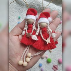 two red and white christmas ornaments are held in someone's hand with beads on it