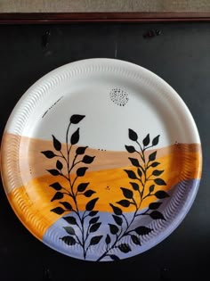 a paper plate with leaves painted on the outside and yellow in the middle, sitting on a black surface