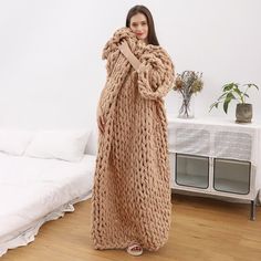 a woman wearing a long knitted blanket