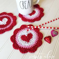 crocheted coasters and coffee cup holder with candy on the side, ready to be used for valentine's day