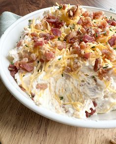 a white plate topped with mashed potatoes covered in bacon and cheddar cheese