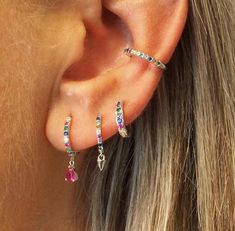 a close up of a woman's ear with three different colored stones on it