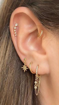 a close up of a person with ear piercings on their ears and wearing gold jewelry