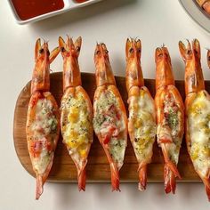 there are many shrimp on the cutting board next to some sauces and a plate