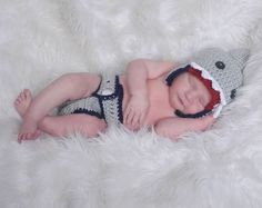 a baby wearing a crochet hat and diaper laying on a white blanket