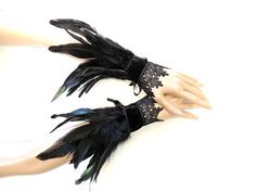 two hands with black and blue feathers attached to each other on top of a mannequin's head