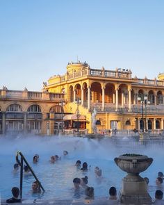 many people are in the water near a large building with columns and balconies