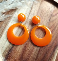 I have made these fabulous statement drop hoop earrings in resin, using vibrant orange colouring. The drop hoops have a classic 1950's style and measure 42mm in diameter. They are fixed to the top studs which are 17mm in diameter and have a 6mm dome. They are finished with silver tone brass earring posts and have an total drop of 62mm. They are incredibly lightweight making them easy to wear. They will look amazing with your vintage summer dresses and also jeans and tops for a 50's rockabilly look. Please get in touch if you'd like these in a different colour combination, tops and hoops can be mixed or alternated if you would like mis-matched earrings. You can find more of my 50s and 60s drop hoop earrings here: www.etsy.com/uk/shop/RosieMays?section_id=25135598 Thank you for visiting. Jeans And Tops, 60s Earrings, 70s Earrings, Rockabilly Looks, Orange Retro, Drop Hoop Earrings, Resin Jewellery, Orange Earrings, Vintage Summer Dresses