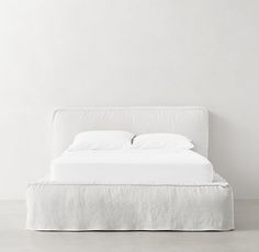 a bed with white sheets and pillows on top of it in a room next to a wall