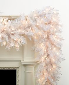 a white christmas garland hanging from the side of a fireplace