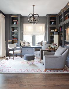 a living room filled with furniture and bookshelves next to a window covered in curtains