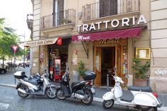 three scooters are parked in front of a restaurant on the side of the street