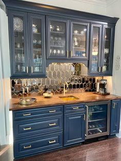 a kitchen with blue cabinets and wooden counter tops, gold accents on the backsplash