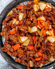 a bowl filled with meat and vegetables on top of a table next to utensils