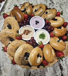 an assortment of bagels and fruit arranged in a circular arrangement on a marble surface