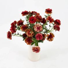 a white vase filled with red and orange flowers