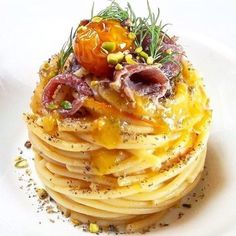 a white plate topped with pasta covered in toppings