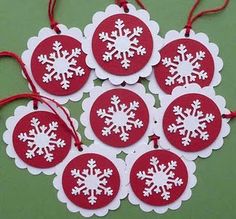 six red and white snowflake ornaments on a green tablecloth with twine