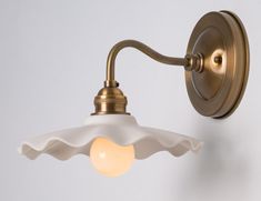 an antique brass wall light with a white glass shade on the arm and one light bulb