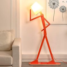 an orange floor lamp with a white light on it in a living room next to a couch