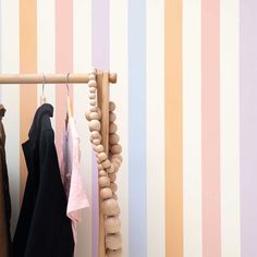 clothes hanging on a rack in front of striped wallpaper