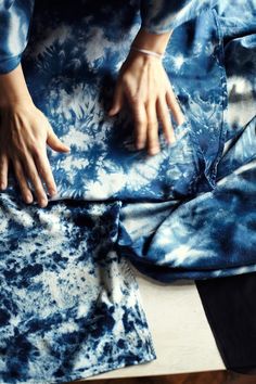 a person's hands on top of a blue tie - dyed shirt