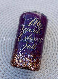 a purple and gold nail polish with some glitter on the top that says, my favorite book is fall