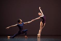 two ballet dancers performing on stage with one holding the other's hand