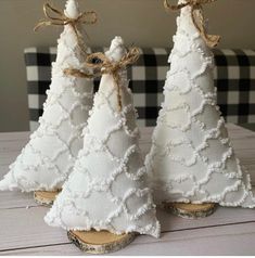 three white christmas trees are sitting on wood planks with burlocks around them