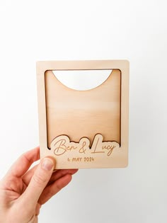 a person holding up a laser cut wooden card