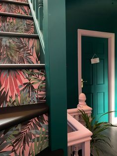 the stairs are decorated with tropical wallpaper and palm leaves on pink and green walls