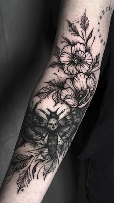 a woman's arm with flowers and an owl tattoo on the left forearm, in black and white