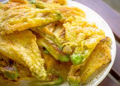 some fried food on a white plate with green peppers and sauces in the background