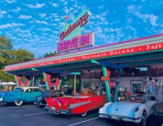 several classic cars are parked in front of a drive - in