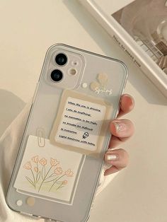 a person holding a cell phone case with flowers on the back and a note attached to it