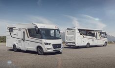 two white motorhomes parked in an empty lot