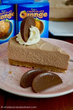 a piece of chocolate cheesecake on a pink plate with two boxes of oranges