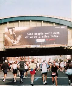 there are many people walking down the street in front of a large billboard that says some people won't even drive 26 miles today