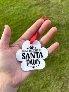 someone is holding up a dog ornament that says, don't believe in santa paws