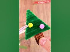 a hand holding a green felt christmas tree ornament