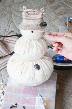 a snowman made out of sweaters and buttons sitting on top of a table