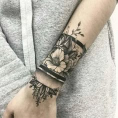 a woman's arm with a flower tattoo on it and a black ribbon around the wrist