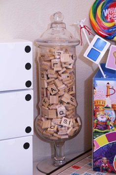 a glass jar filled with lots of wooden blocks next to a box of magnets