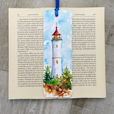 an open book with a watercolor painting of a lighthouse on it's cover