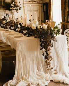 a long table with white cloths and flowers on it is set up for a formal dinner