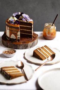 a cake sitting on top of a white table next to two plates with desserts